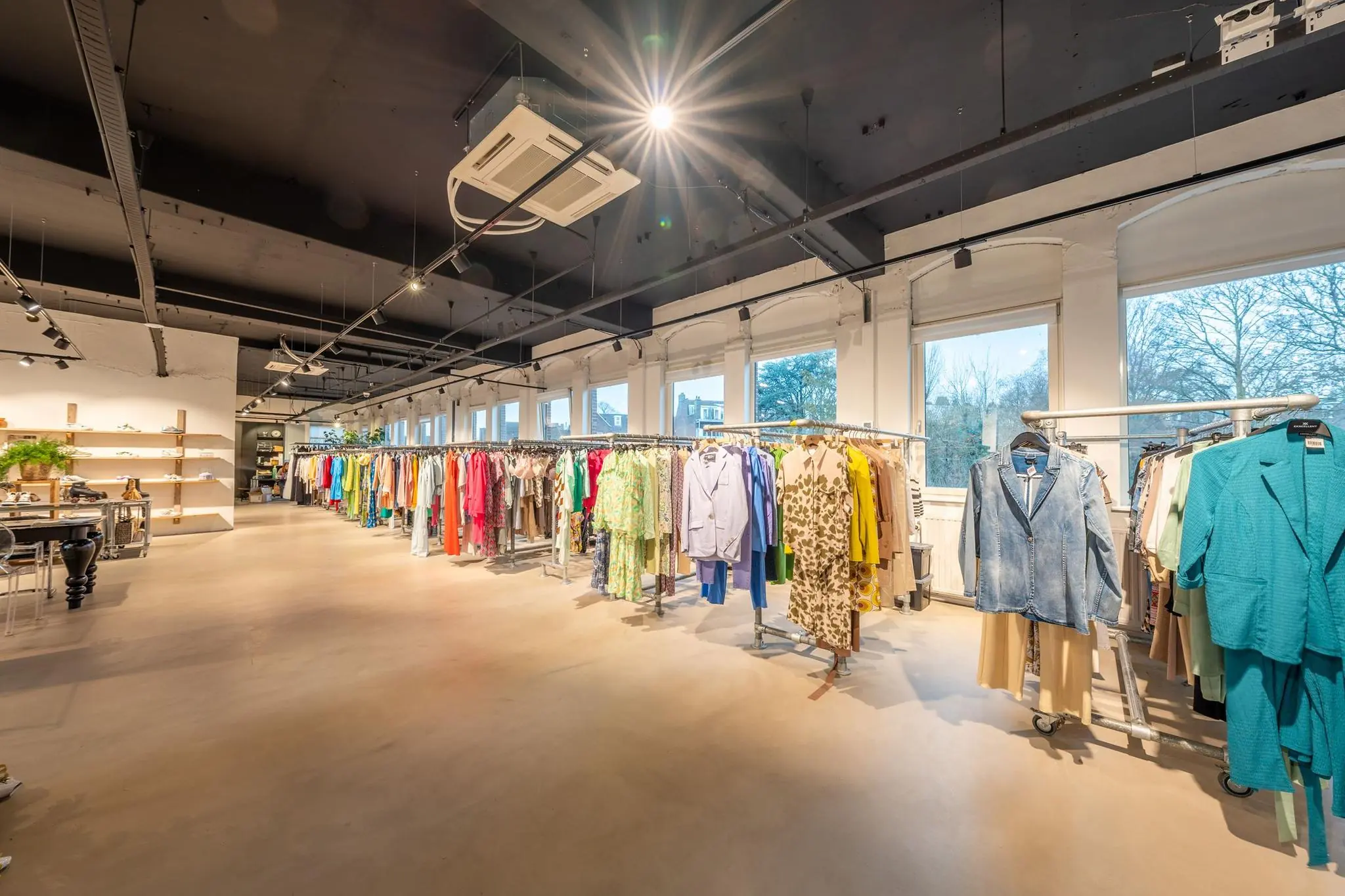 Ruime en licht ingerichte kledingwinkel aan de Admiraal de Ruijterweg met kleurrijke dameskleding op rekken.